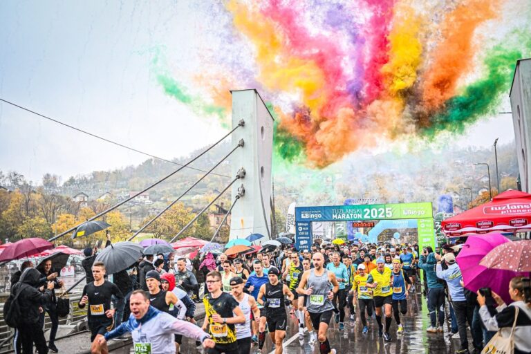 Start Tuzlanskog maratona 2025 na mostu, oblaci šarenog dima iznad trkača i kišobrana