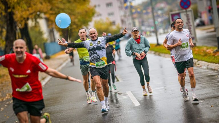 Grupa trkača sa plavim balonom tempomajstora trči kroz grad